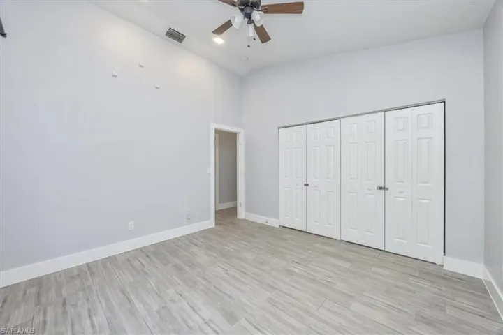 Unfurnished bedroom featuring light wood-style flooring, high vaulted ceiling, ceiling fan, and a closet