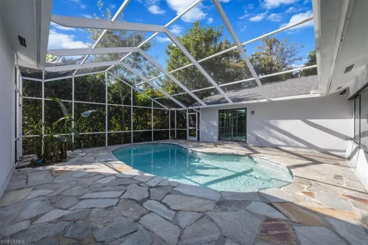 Outdoor pool featuring a patio, glass enclosure, and a sunroom