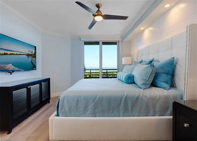 Bedroom featuring floor to ceiling sliding doors with Gulf views, access to exterior, ceiling fan, light hardwood / wood floors, and ornamental molding