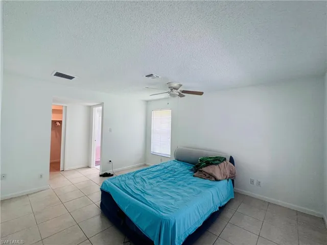 Tiled bedroom featuring a textured ceiling and ceiling fan