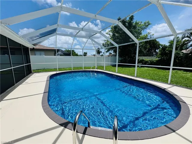 View of swimming pool featuring a lanai and a lawn
