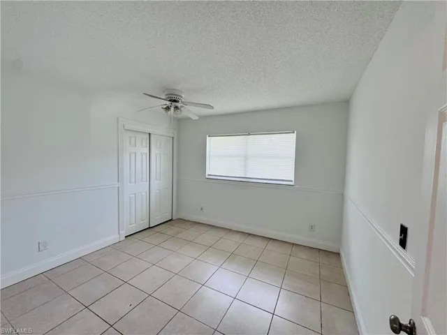 Tiled spare room featuring a textured ceiling and ceiling fan