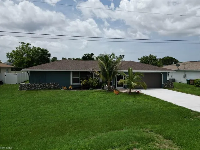 Ranch-style house featuring a garage and a front yard