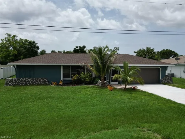 Ranch-style house featuring a garage, central AC unit, and a front yard