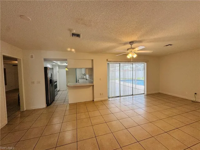 Tiled empty room featuring a textured ceiling and ceiling fan