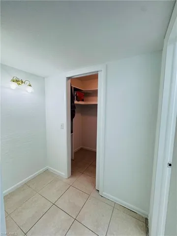 Unfurnished bedroom featuring light tile patterned flooring, a closet, and a spacious closet