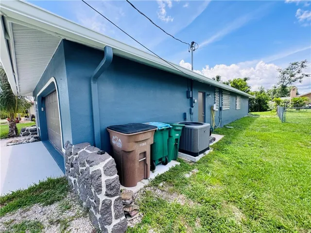 View of property exterior featuring a garage, a yard, and central air condition unit