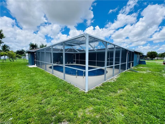 Rear view of property with glass enclosure and a yard