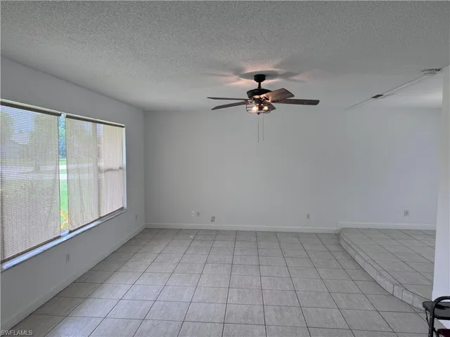 Unfurnished room featuring a textured ceiling, a healthy amount of sunlight, light tile patterned floors, and ceiling fan