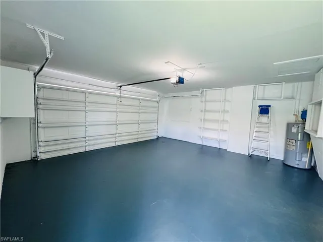 Garage featuring electric water heater and a garage door opener