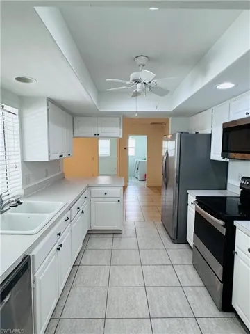 Kitchen with plenty of natural light, ceiling fan, a raised ceiling, and stainless steel appliances