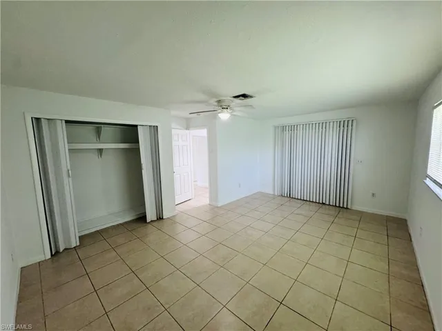 Unfurnished bedroom with light tile patterned floors, a closet, and ceiling fan