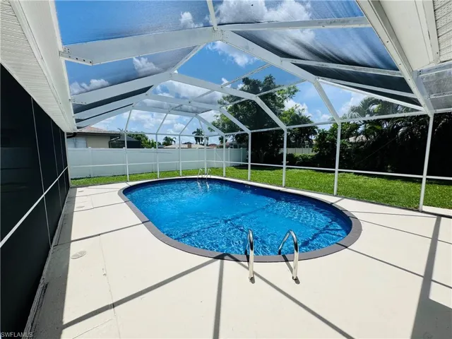 View of swimming pool featuring a patio, a lanai, and a lawn