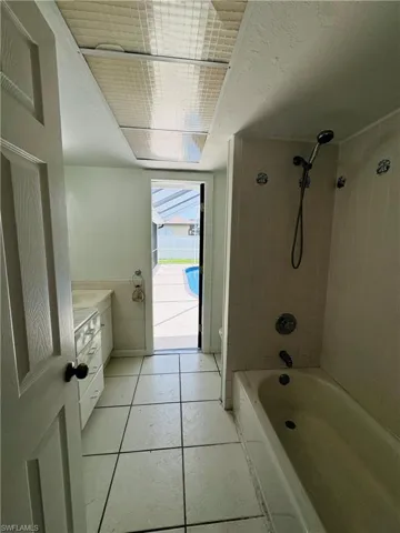 Bathroom with tiled shower / bath combo, vanity, and tile patterned flooring