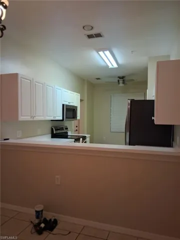 Kitchen featuring light countertops, a peninsula, stainless steel appliances, and light tile patterned floors