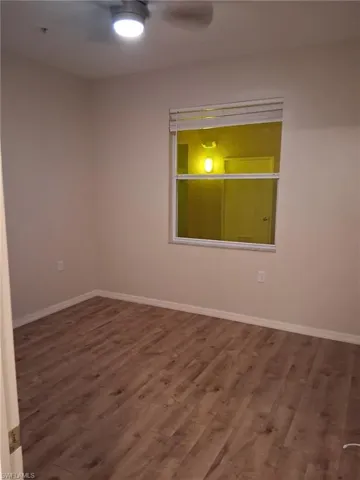 Unfurnished room with dark wood finished floors and ceiling fan
