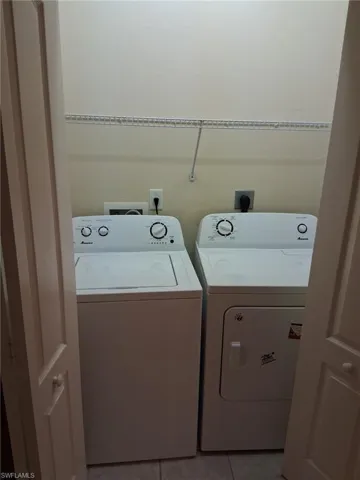 Laundry area with light tile patterned flooring and washing machine and dryer