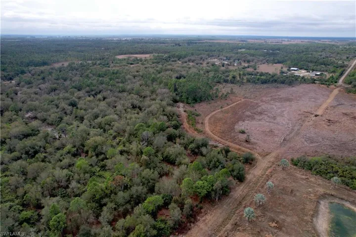 Aerial view of property and surrounding area with a heavily wooded area