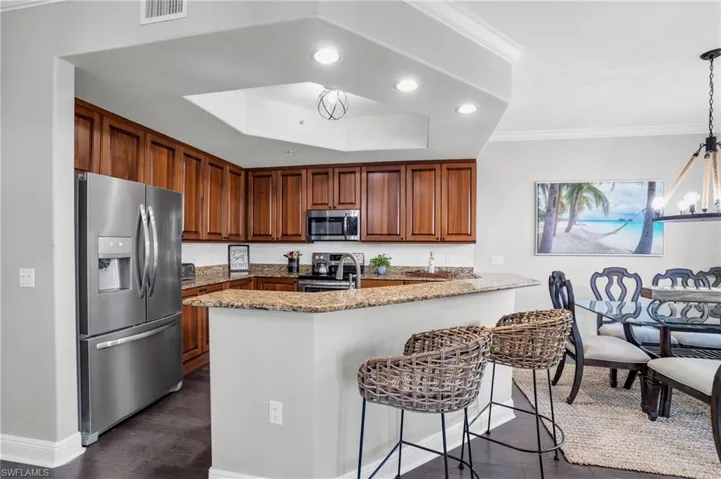 Kitchen featuring stainless steel appliances, recessed lighting, a chandelier, light stone counters, and a peninsula