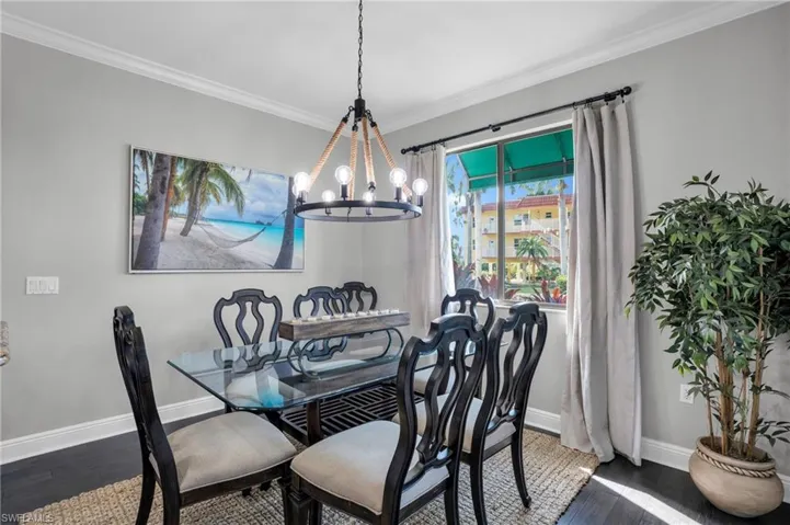 Dining room featuring ornamental molding, a chandelier, and dark wood-style flooring
