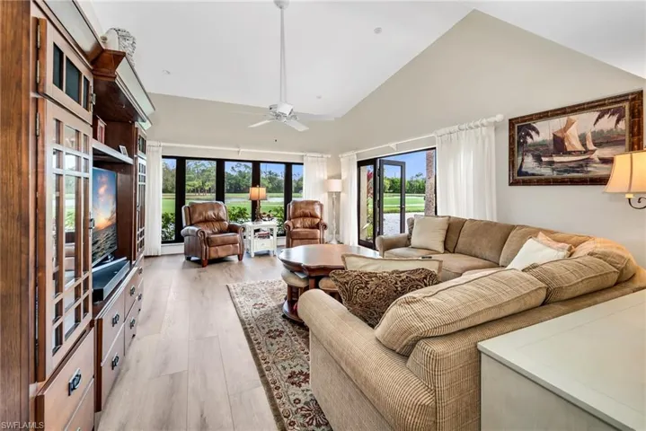Living room featuring lofted ceiling, ceiling fan, and light wood finished floors