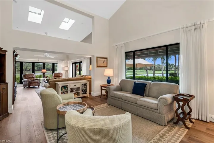 Living room with a skylight, wood finished floors, vaulted ceiling, and a ceiling fan