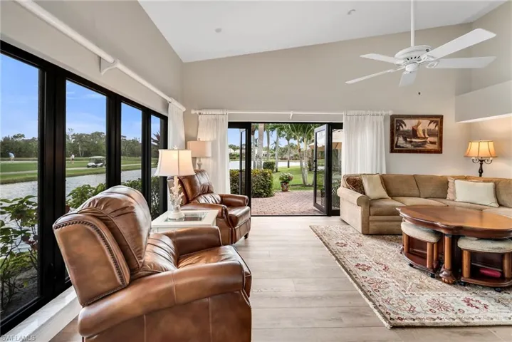 Living area featuring vaulted ceiling, light wood-style floors, a water view, and a ceiling fan