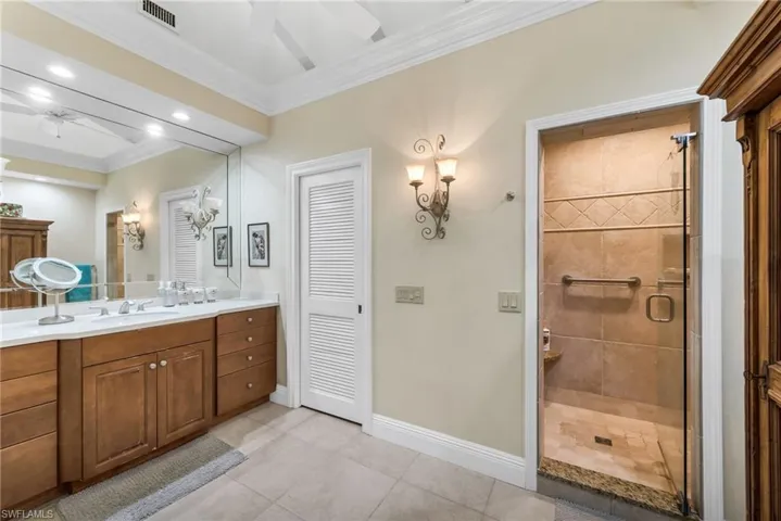 Full bath with vanity, ornamental molding, ceiling fan, a shower stall, and light tile patterned floors