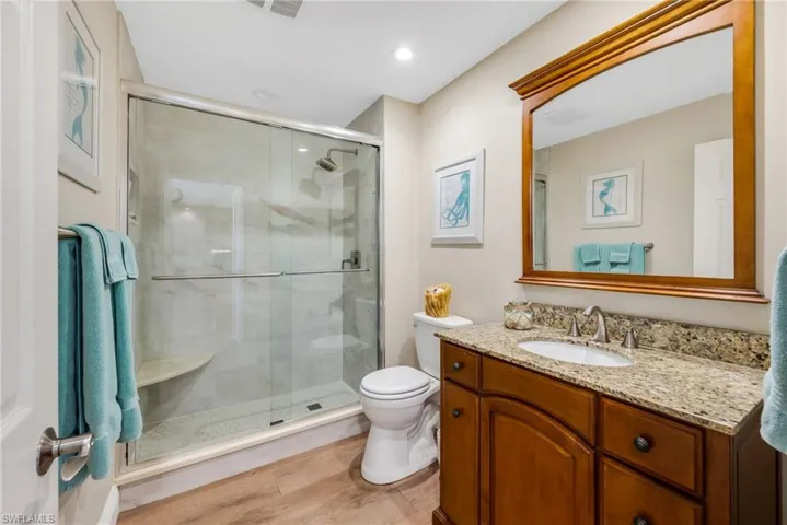 Bathroom featuring vanity, a stall shower, light wood-type flooring, and recessed lighting