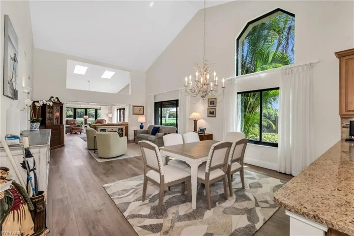 Dining area with hanging lights, light wood finished floors, lofted ceiling, and a skylight