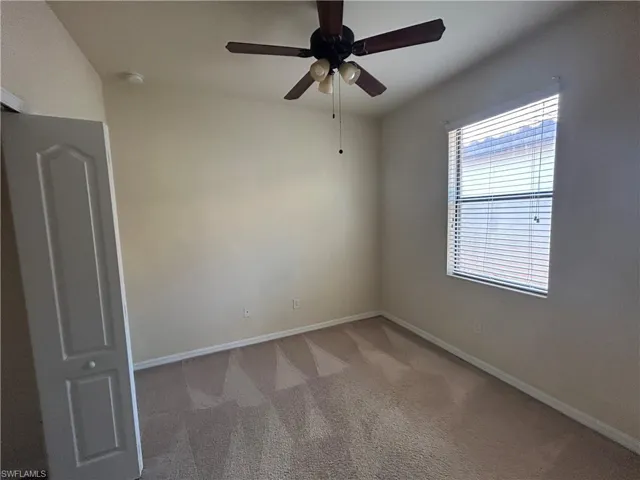 Carpeted spare room featuring a ceiling fan and baseboards