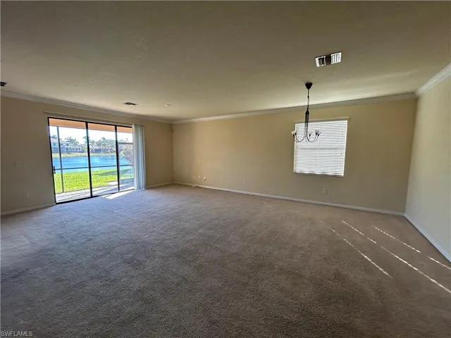 Spare room with a water view, carpet floors, crown molding, and suspended lighting