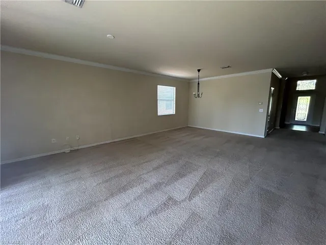 Carpeted spare room with ornamental molding and baseboards
