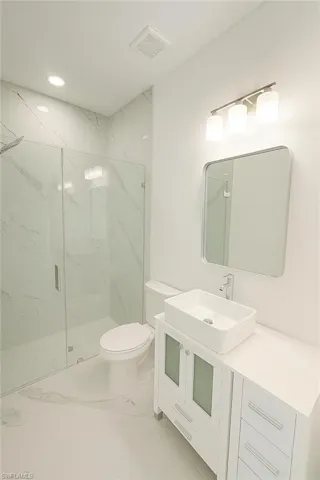 Full bathroom with vanity, light marble finish floors, a marble finish shower, and recessed lighting