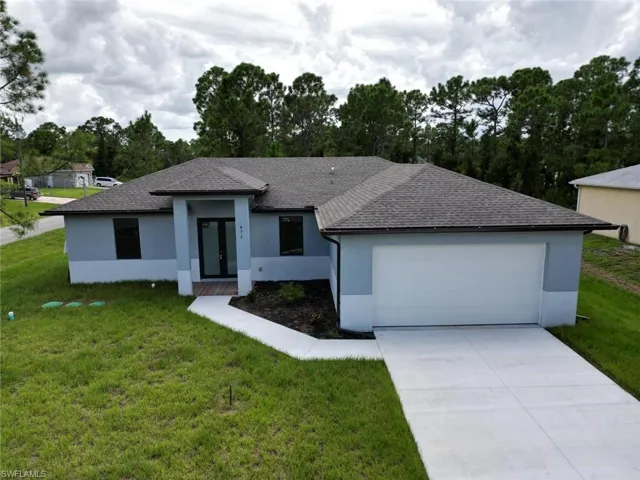 View of front of house with stucco siding, a shingled roof, a front yard, and concrete driveway