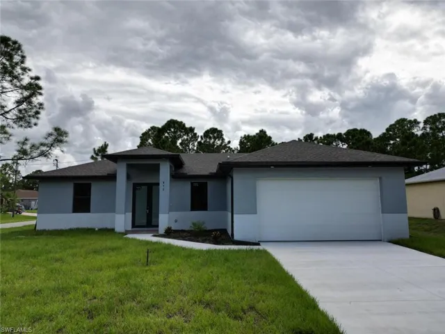 Prairie-style home with stucco siding, a front yard, and concrete driveway