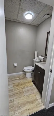 Bathroom featuring a drop ceiling, vanity, and wood tiled floors