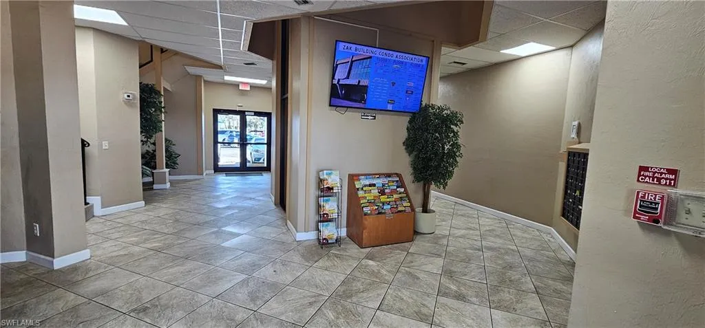 Corridor featuring a paneled ceiling and a textured wall