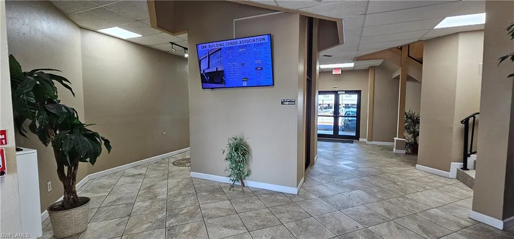 Corridor featuring a drop ceiling and light tile patterned floors