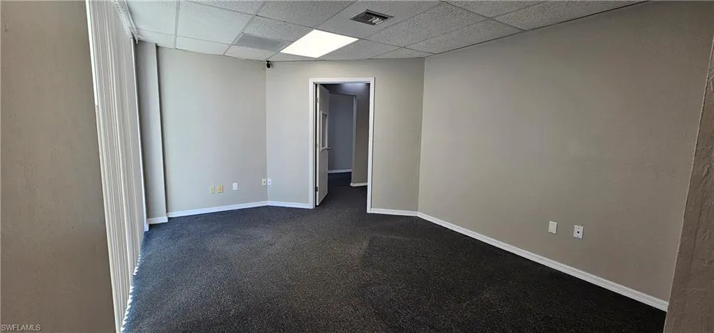 Spare room with a paneled ceiling and dark carpet