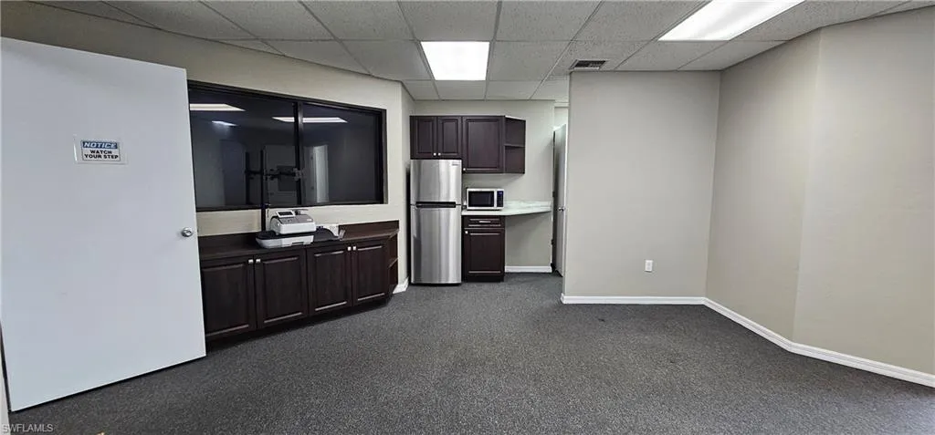 Kitchen with dark wood finish cabinets, stainless steel appliances, a paneled ceiling, and light countertops