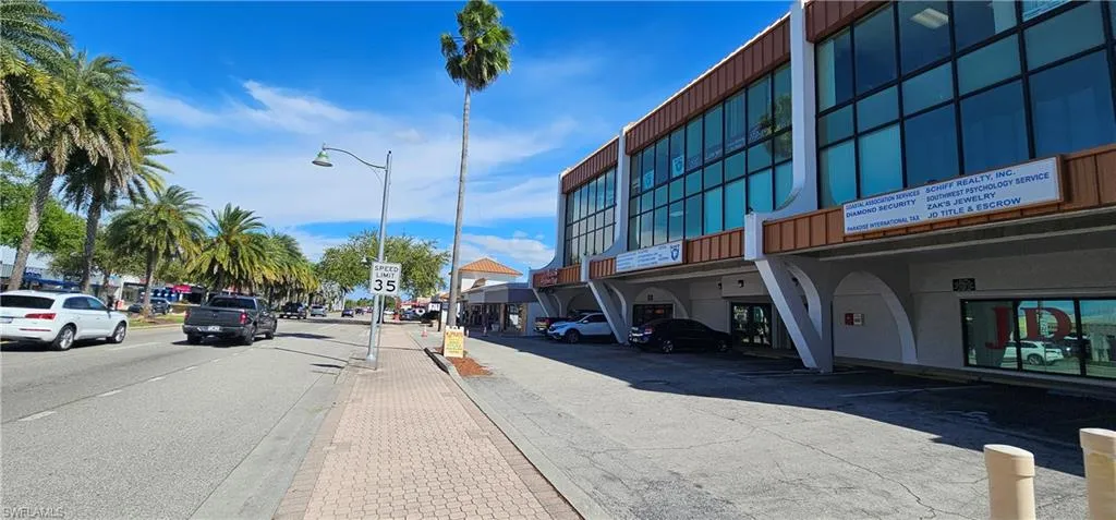 View of asphalt street featuring street lights, sidewalks, traffic signs, and curbs