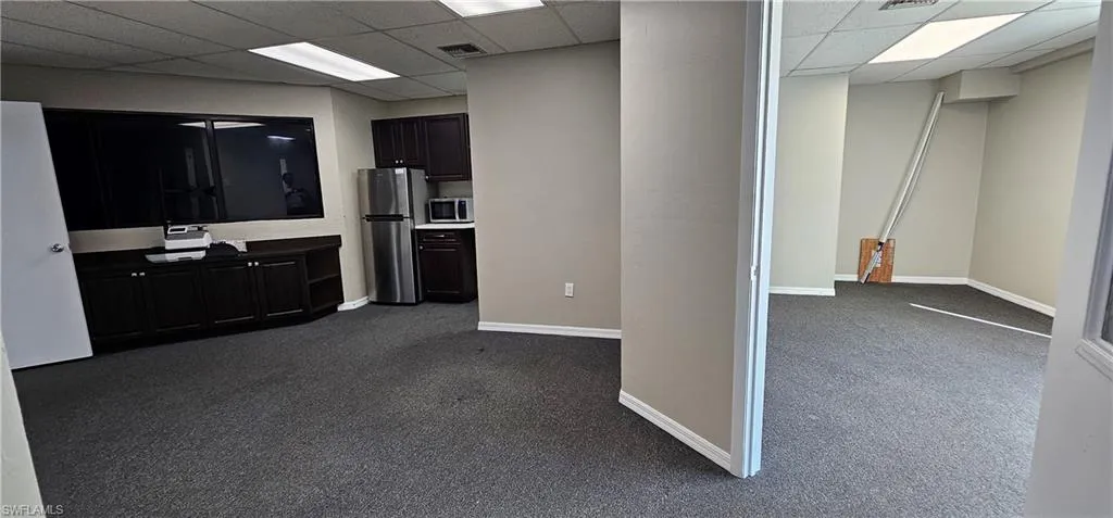 Kitchen with dark carpet, stainless steel appliances, a drop ceiling, and dark wood finish cabinets