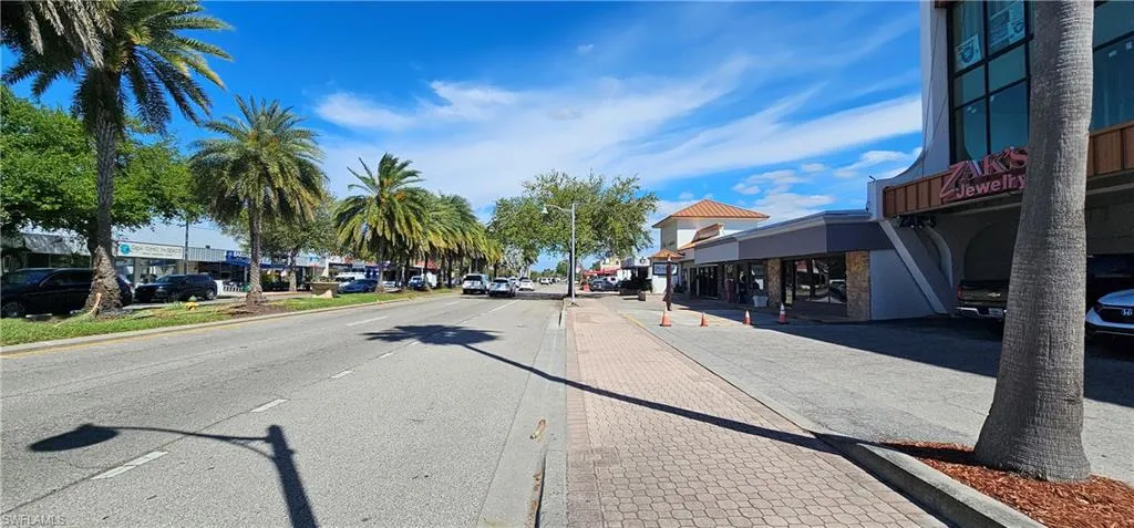 View of asphalt street featuring curbs, street lighting, and sidewalks