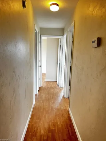 Corridor featuring wood finished floors and a textured wall