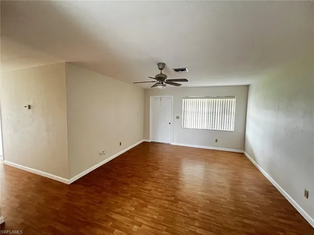 Unfurnished room featuring dark wood-style flooring and a ceiling fan