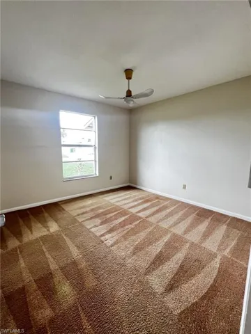 Carpeted spare room with baseboards and a ceiling fan