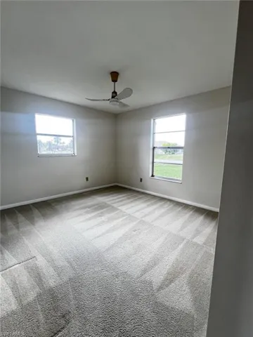 Empty room with carpet, a ceiling fan, and healthy amount of natural light