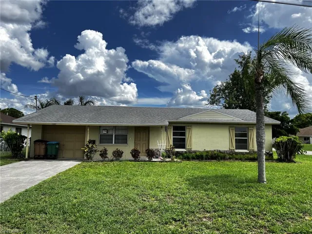 Ranch-style house featuring stucco siding, a front lawn, an attached garage, and roof with shingles