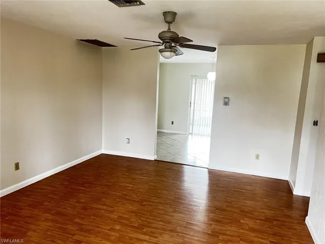 Empty room with ceiling fan and dark wood finished floors